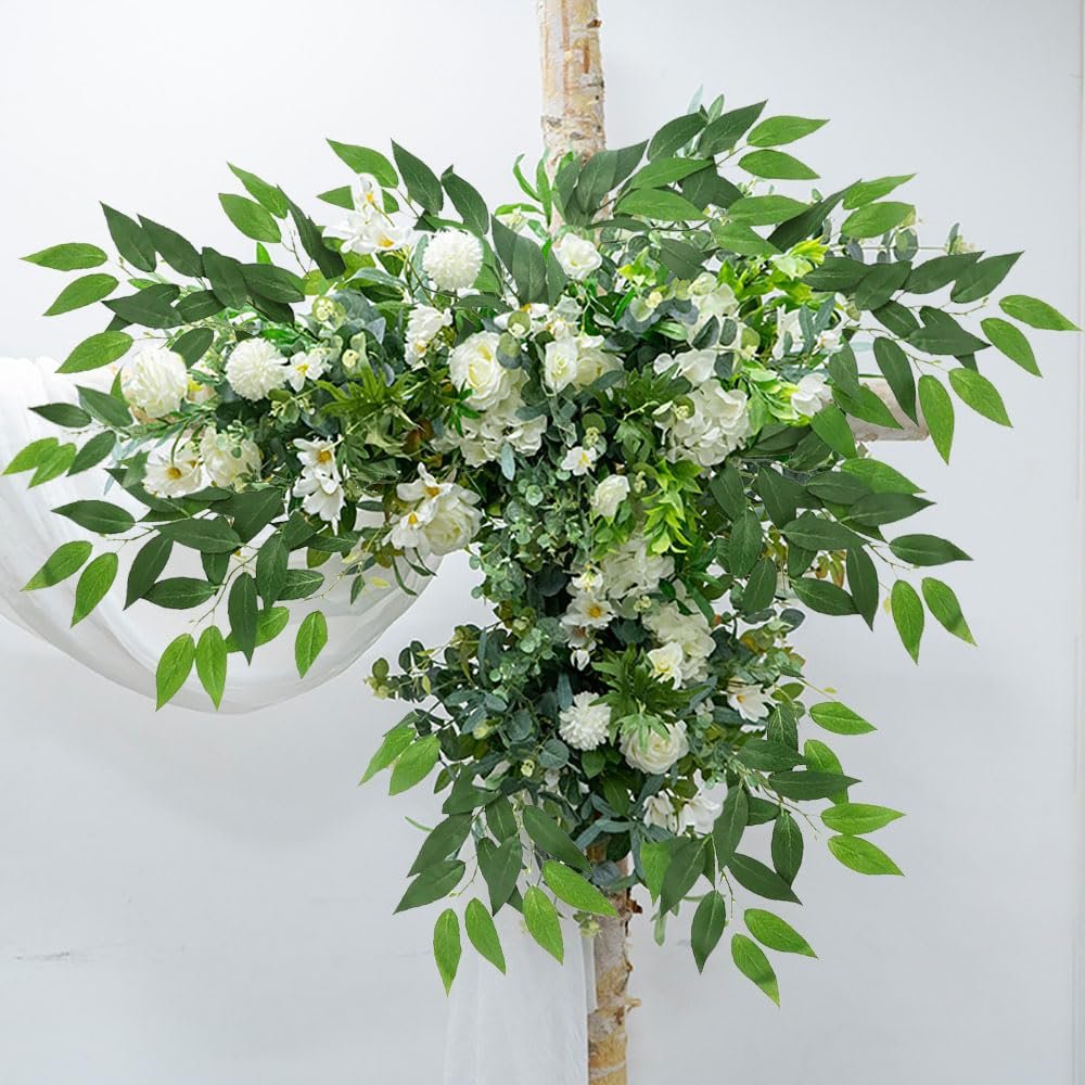 Artificial Italian Ruscus greenery stems with white roses and other flowers arranged on a birch branch against a white background.