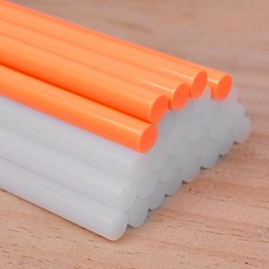 Stack of orange and white full-size glue sticks on a wooden surface