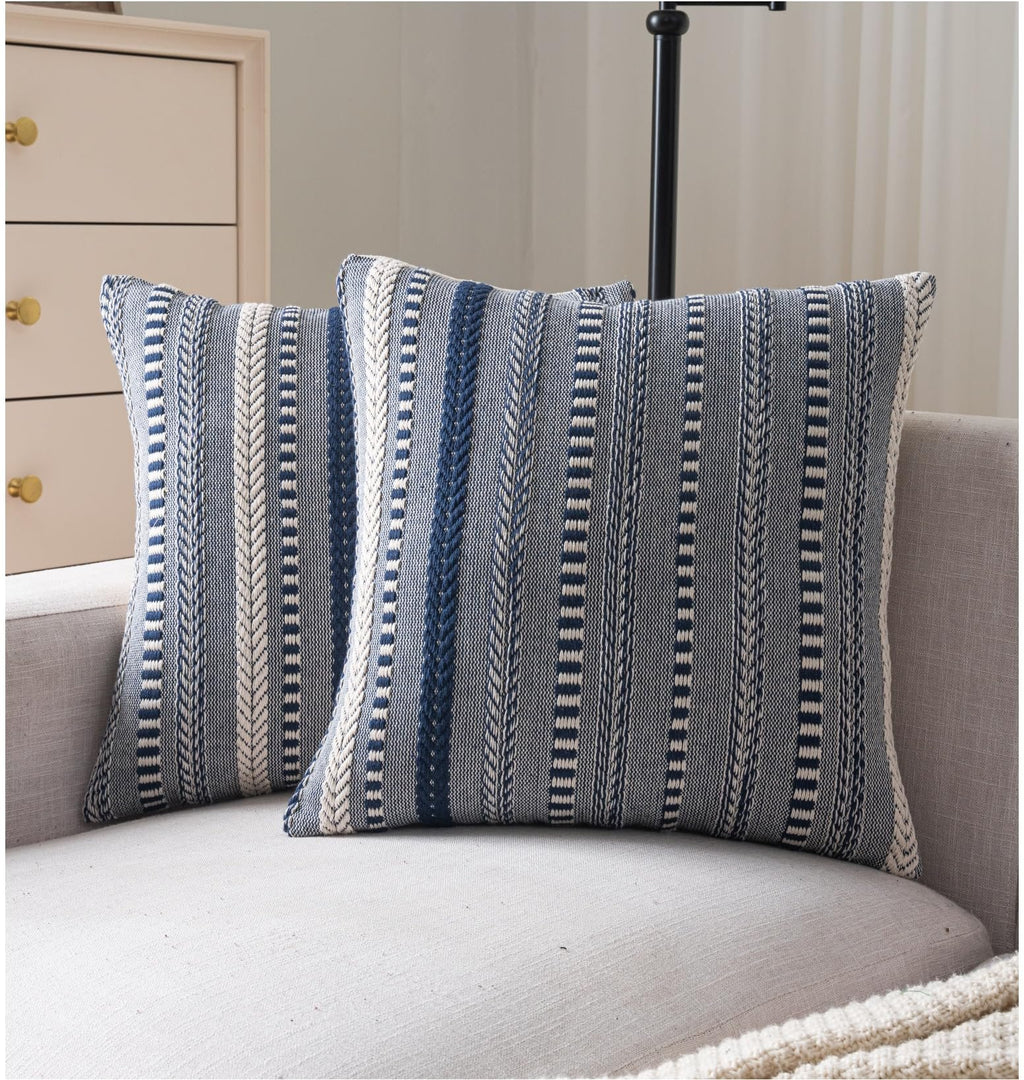 Two navy blue and white striped boho throw pillow covers on a sofa.