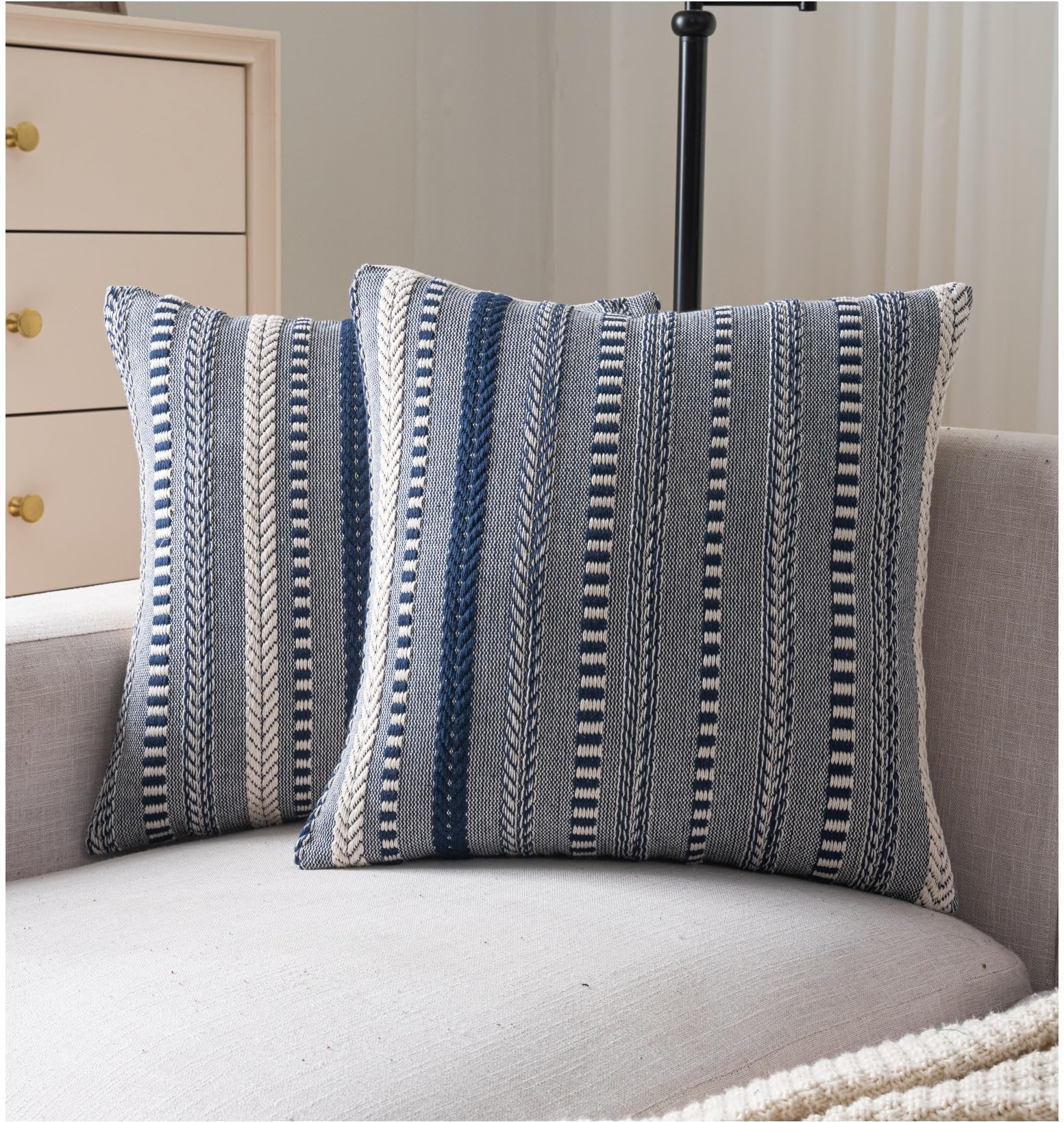 Two navy blue and white striped boho throw pillow covers on a sofa.
