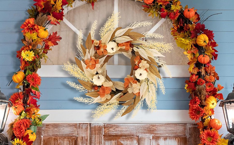 Artificial fall wreath with white pumpkins, orange and yellow leaves, and flowers, displayed on a blue-sided house with white trim.