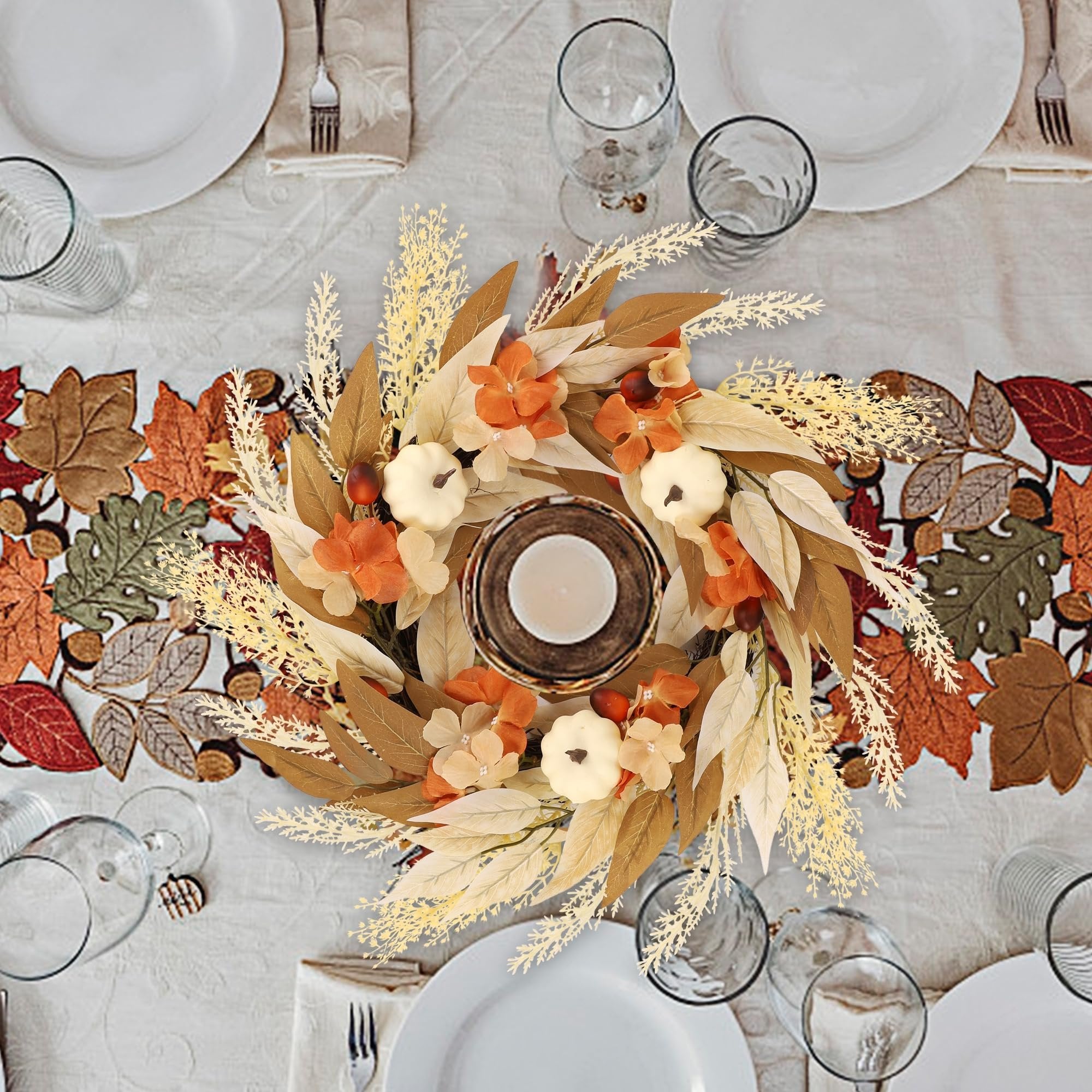 Artificial fall wreath with white pumpkins, orange flowers, and autumn leaves on a table setting