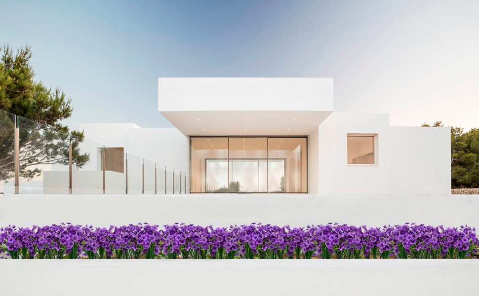 Row of purple artificial flowers in front of a modern white house with glass doors and windows