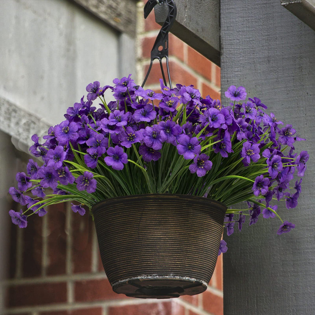 Hanging basket filled with purple artificial flowers and green plastic foliage, suspended from a hook.