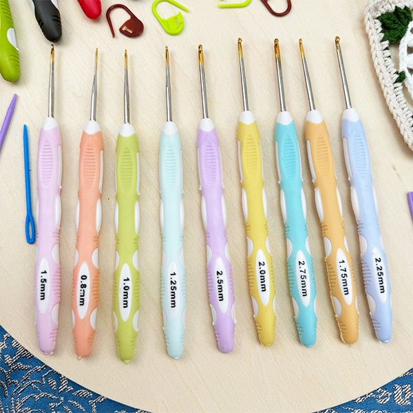 Set of colorful crochet hooks with size markings, arranged on a wooden surface with crochet accessories.