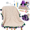 Crochet blanket kit with yarn balls, crochet hooks, tape measure, stitch markers, needles, scissors, and a crocheted flower bouquet.