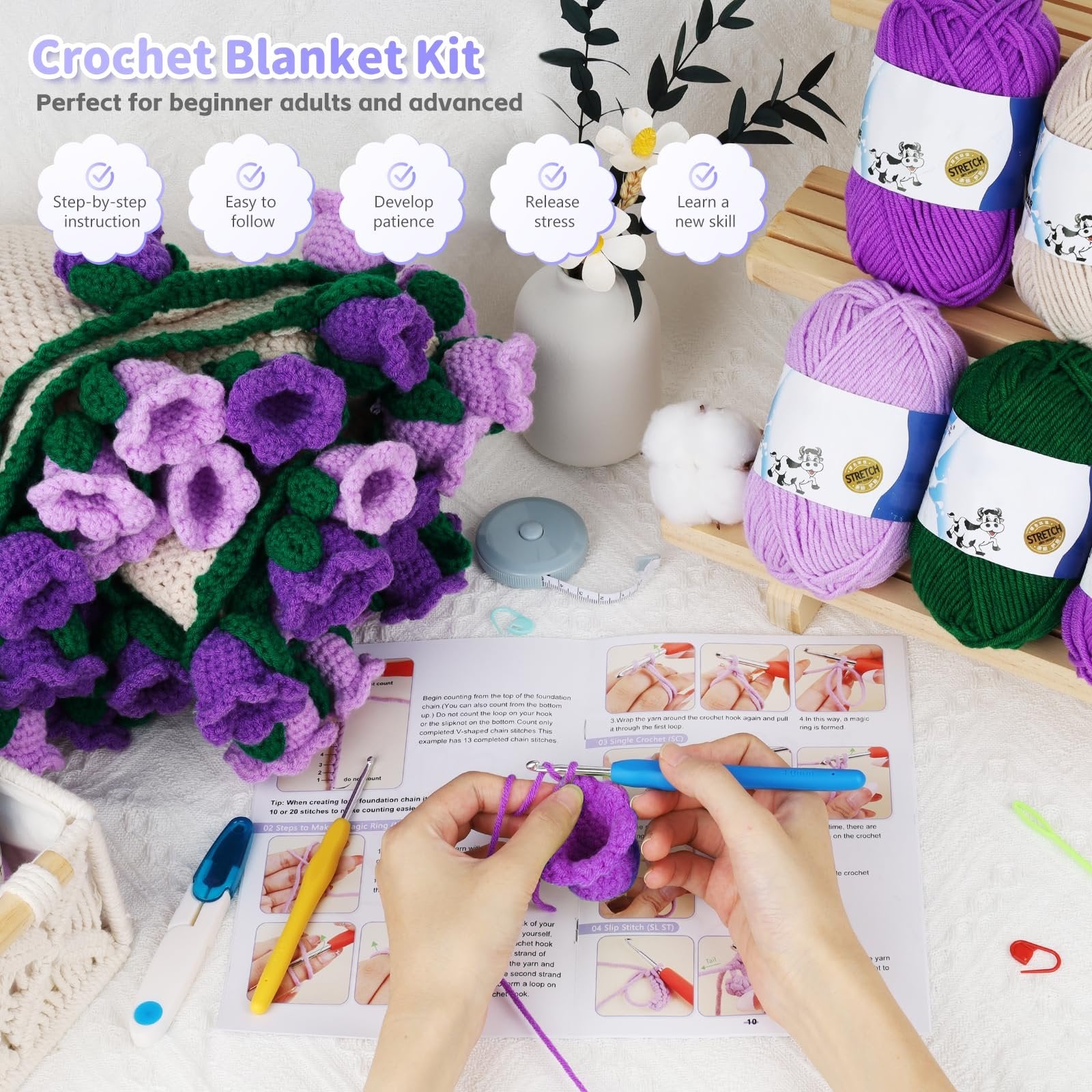 Crochet blanket kit with purple and green yarn flowers, instruction booklet, and crochet hooks. A hand is shown crocheting.