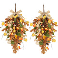 Two fall teardrop swag wreaths with golden eucalyptus and oak leaves, decorated with acorns and tied with burlap bows.