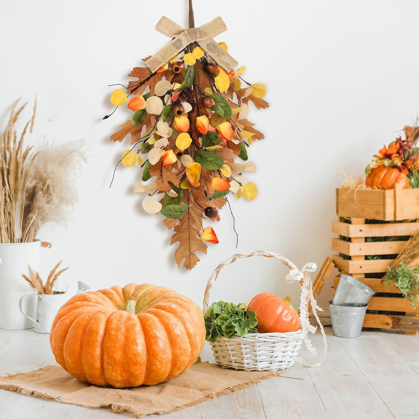 Fall teardrop swag wreath with golden eucalyptus and oak leaves, displayed with pumpkins and autumn decor.