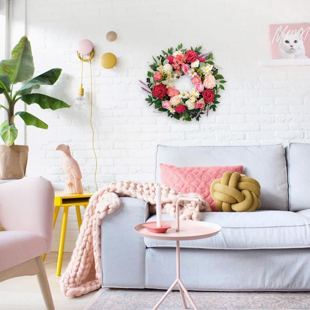 Floral wreath with roses and dahlias hanging on a white brick wall above a sofa.