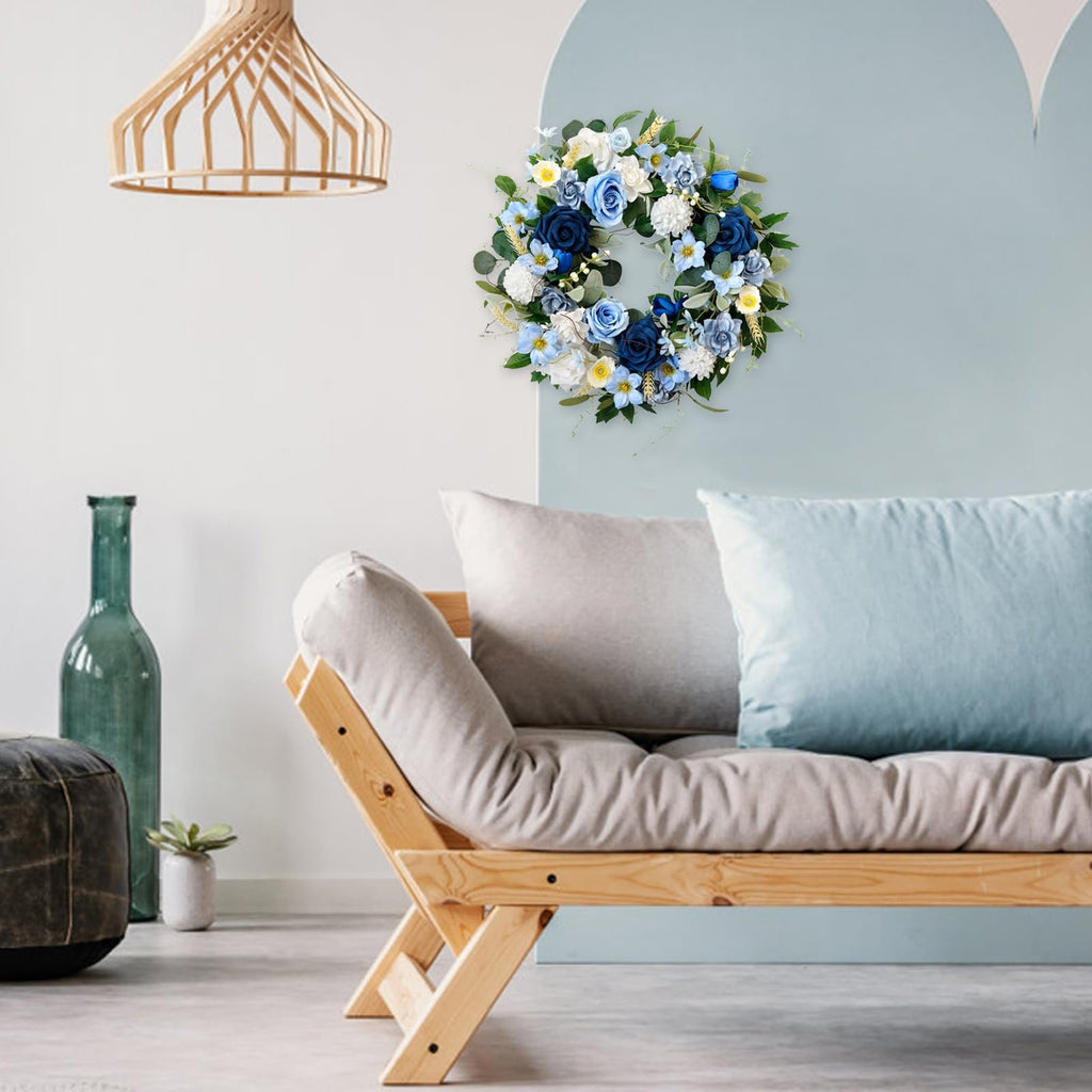 Blue and white floral wreath with roses and hydrangeas hanging on a light blue wall above a sofa