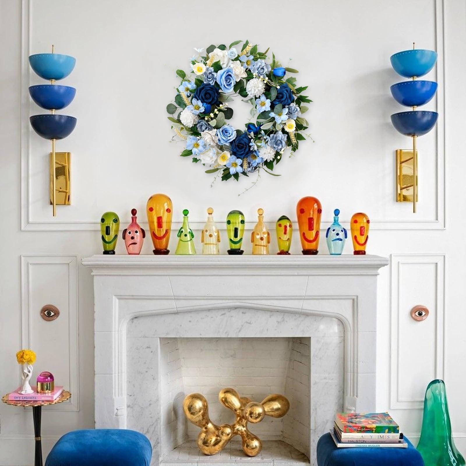 Blue and white floral wreath with green leaves hanging above a fireplace with decorative glass figures.