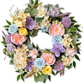Artificial floral wreath with roses, peonies, hydrangeas, and leaves in pastel colors on a white background.