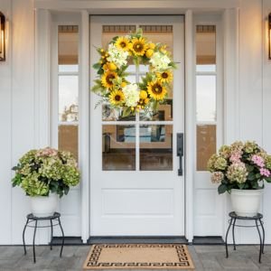 22-inch artificial sunflower wreath with hydrangeas, lemons, and berries hanging on a white front door.