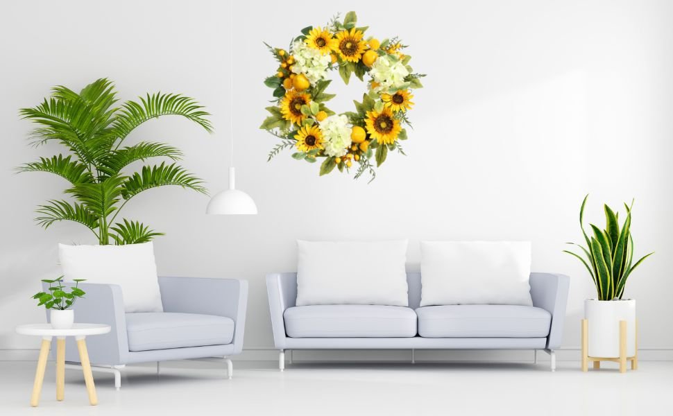 Artificial sunflower wreath with hydrangeas, lemons, and berries hanging on a white wall above a sofa and armchair.