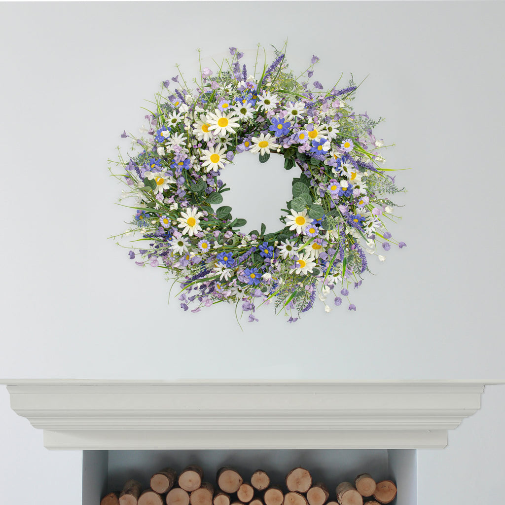 22-inch blue summer wreath with daisies, lavender, wildflowers, and eucalyptus hanging on a wall above a fireplace.