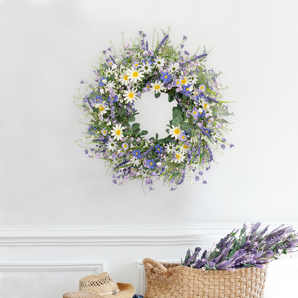 22-inch blue summer wreath with daisies, lavender, wildflowers, and eucalyptus hanging on a white wall above a straw hat and basket of lavender.
