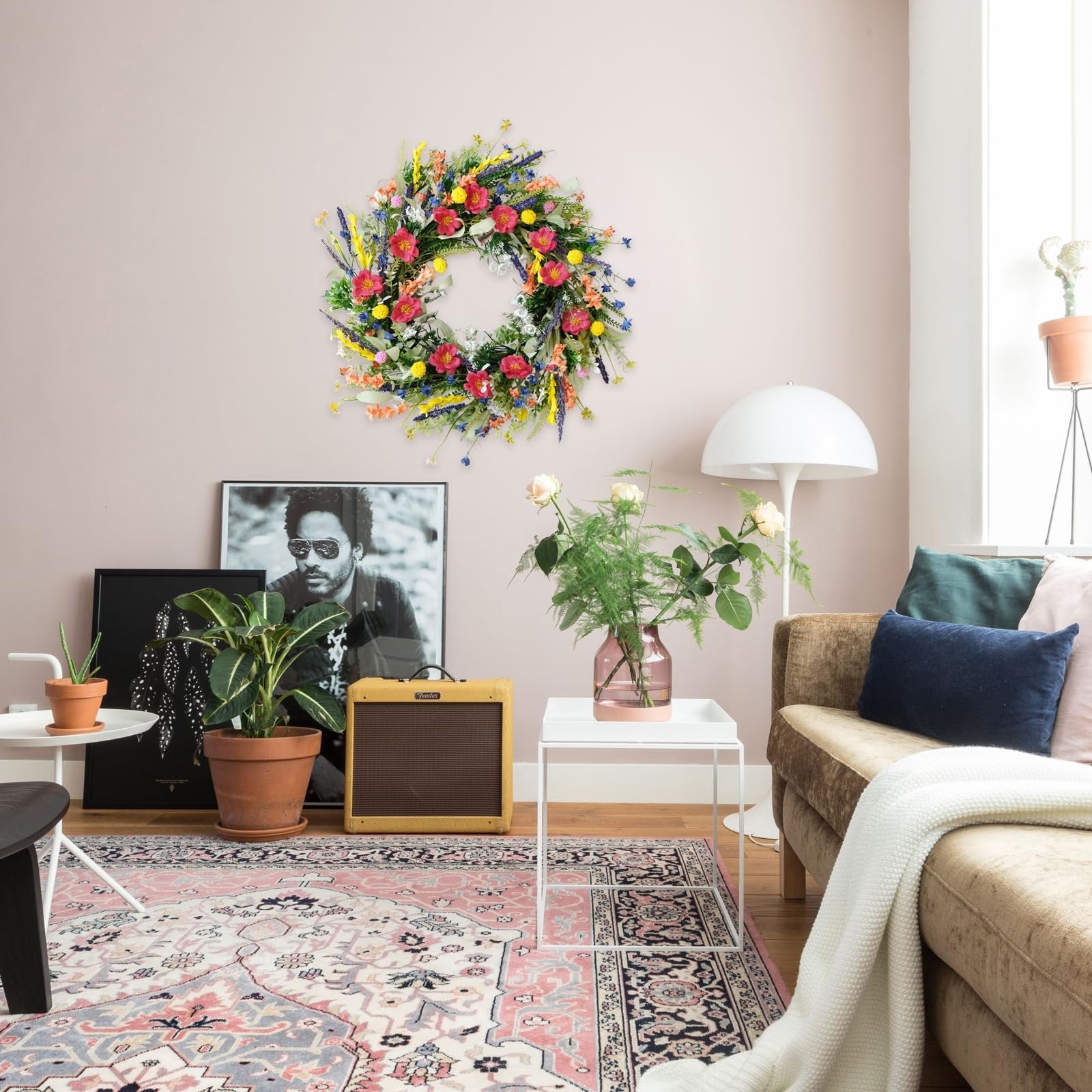 Colorful artificial wildflower and lavender wreath hanging on a wall above a sofa and decorative items.