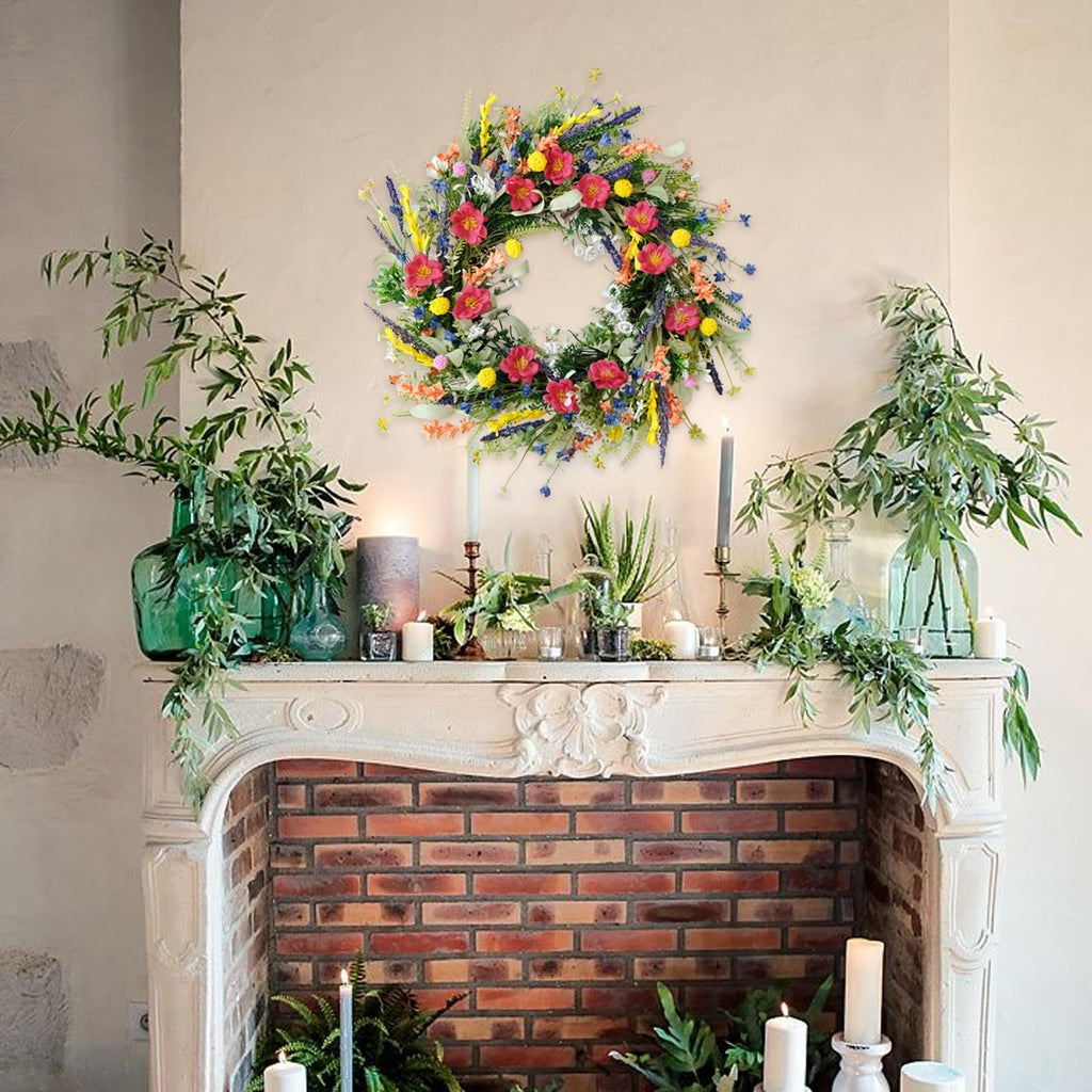 Colorful artificial wildflower and lavender wreath hanging above a fireplace mantel with greenery and candles.