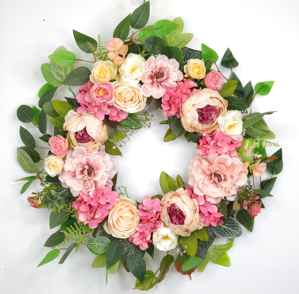 Floral wreath with pink and cream peonies, hydrangeas, and roses on a white background.