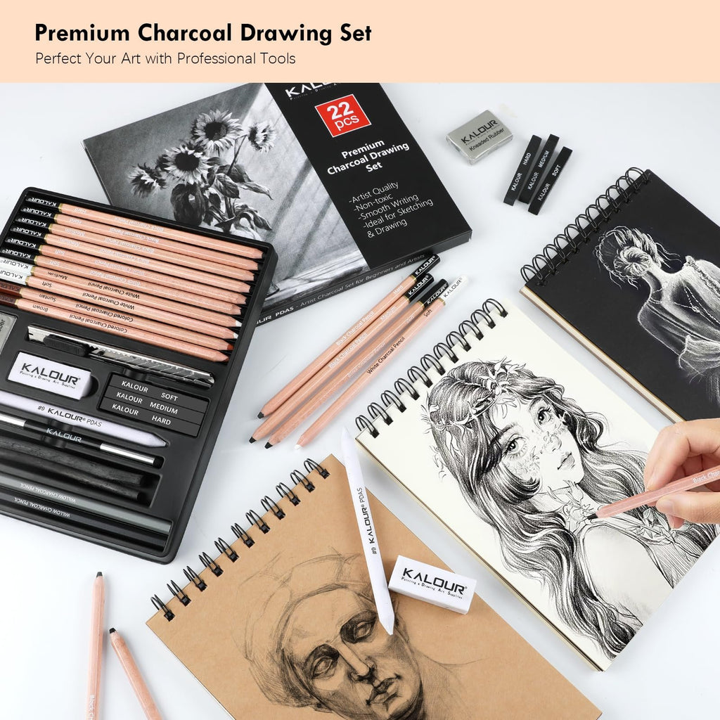 Charcoal drawing set with pencils, sticks, and erasers laid out with sketchbooks and artwork.