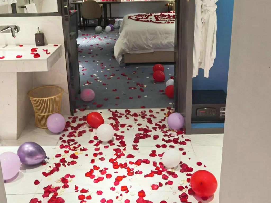 Hotel room decorated with red rose petals and balloons for a romantic occasion