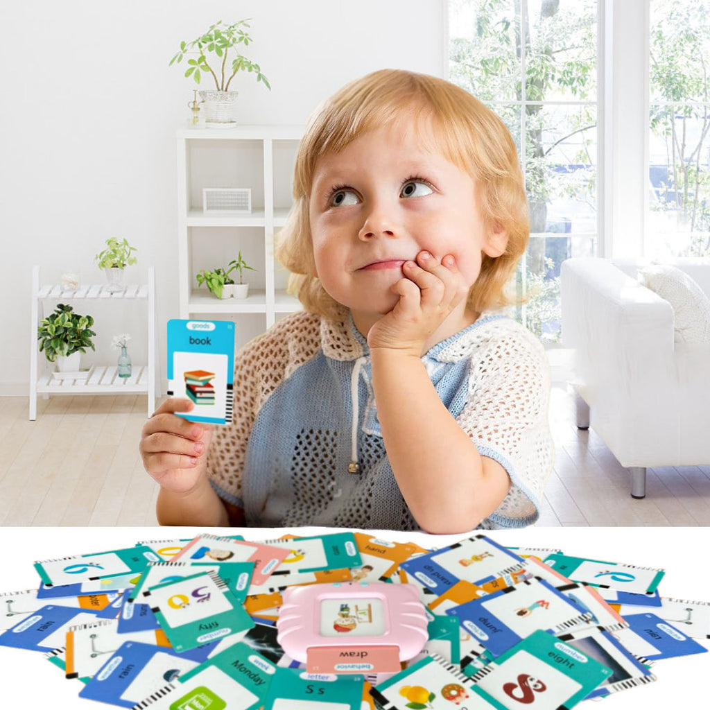 Toddler holding a learning card while a pile of flashcards and a pink learning device are displayed below.