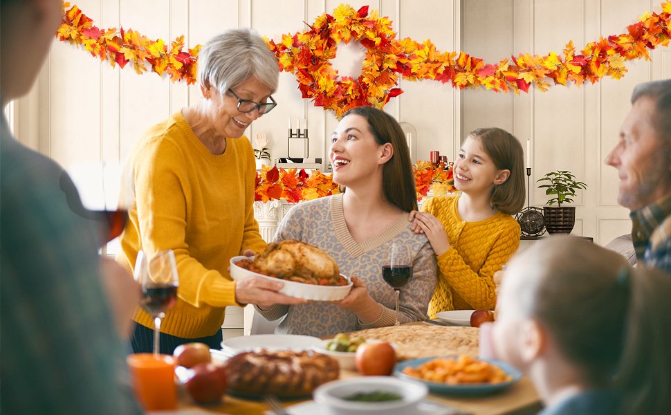 Family gathered around a table for a fall feast, with autumn leaf garlands decorating the background.