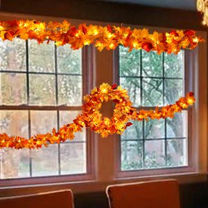 Autumnal maple leaf garland and wreath with warm LED lights draped across a window.