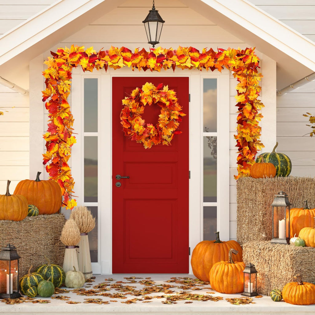 Front porch decorated for fall with a maple leaf garland and wreath, pumpkins, hay bales, and lanterns.