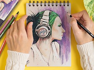 Hands drawing a portrait of a person with headphones on a spiral-bound sketchbook page.