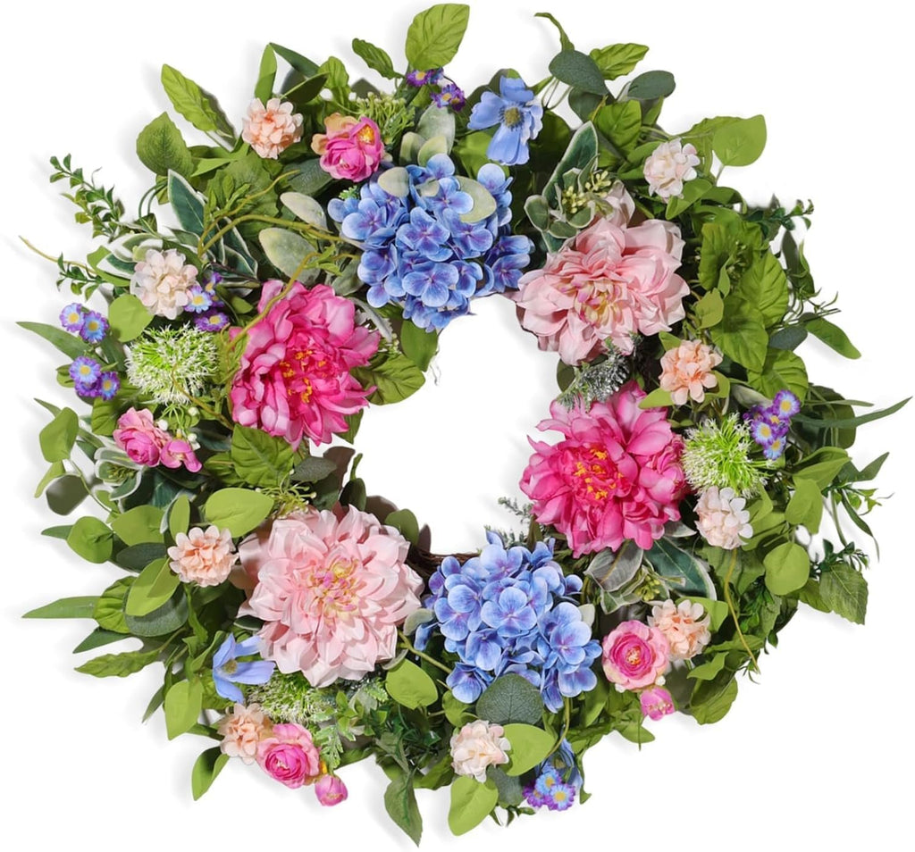 Artificial floral wreath with pink peonies, blue hydrangeas, and green leaves on a white background.