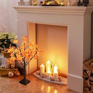 Artificial lighted maple tree with orange-red leaves and 24 LED lights, placed on a floor in front of a fireplace.