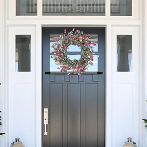 24 inch handmade wreath with EVA leaves and paper flowers hanging on a dark gray front door.