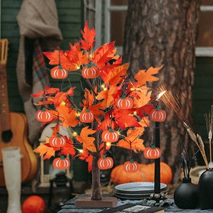 Lighted maple leaves tree with 24 LEDs and 12 wood pumpkin ornaments, set on a table outdoors.