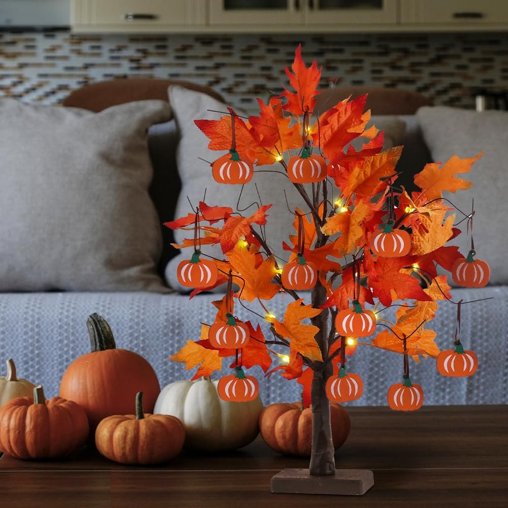 Lighted maple leaves tree with pumpkin ornaments and real pumpkins on a table