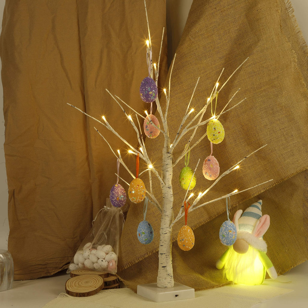 Pre-lit white birch Easter tree with colorful egg ornaments and LED lights, next to a gnome and bag of eggs.