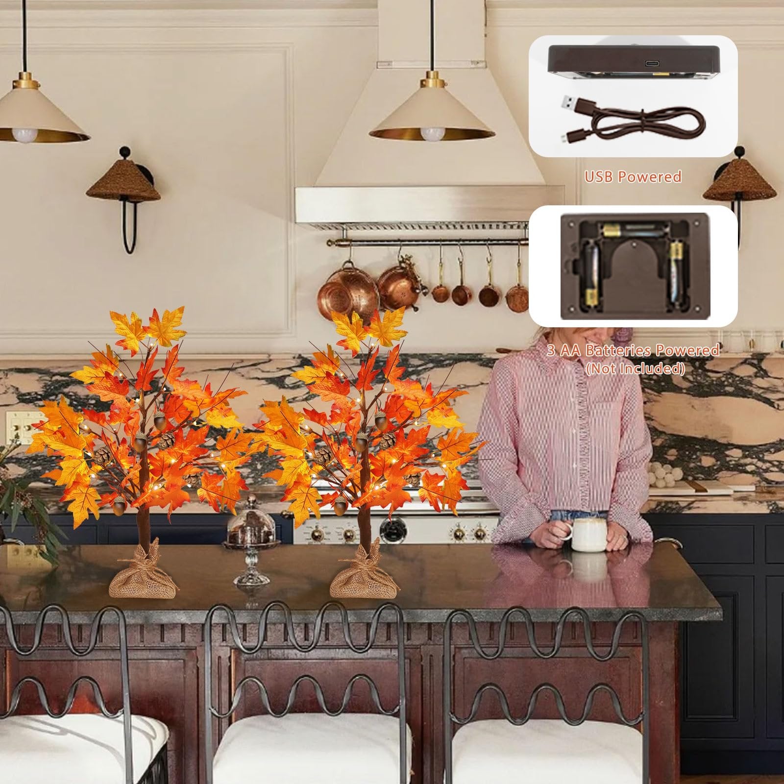 Two artificial maple trees with LED lights, acorns, and pine cones on a kitchen counter. Inset images show USB and battery power options.