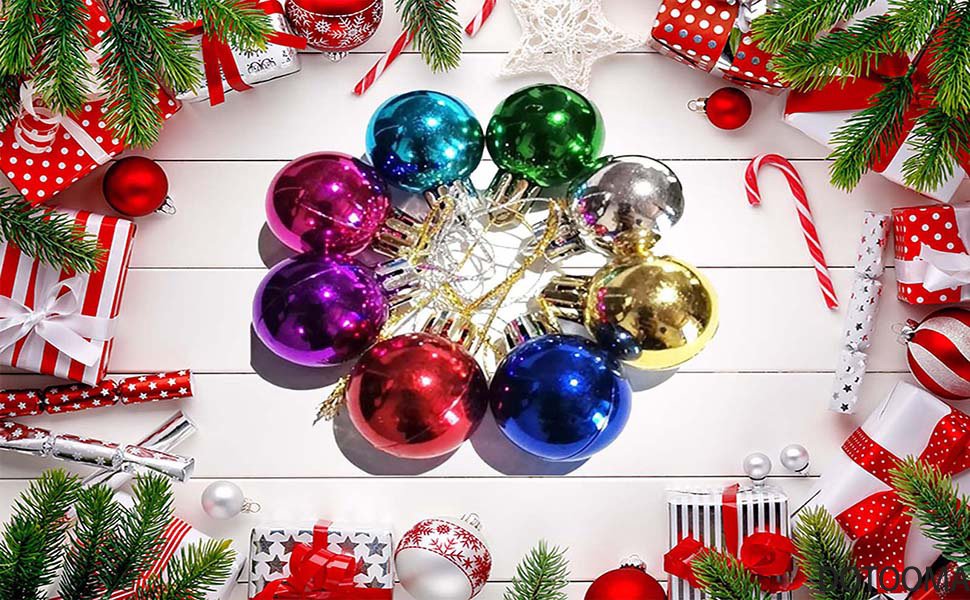 Assortment of colorful Christmas ornaments and gifts arranged on a white wooden surface.