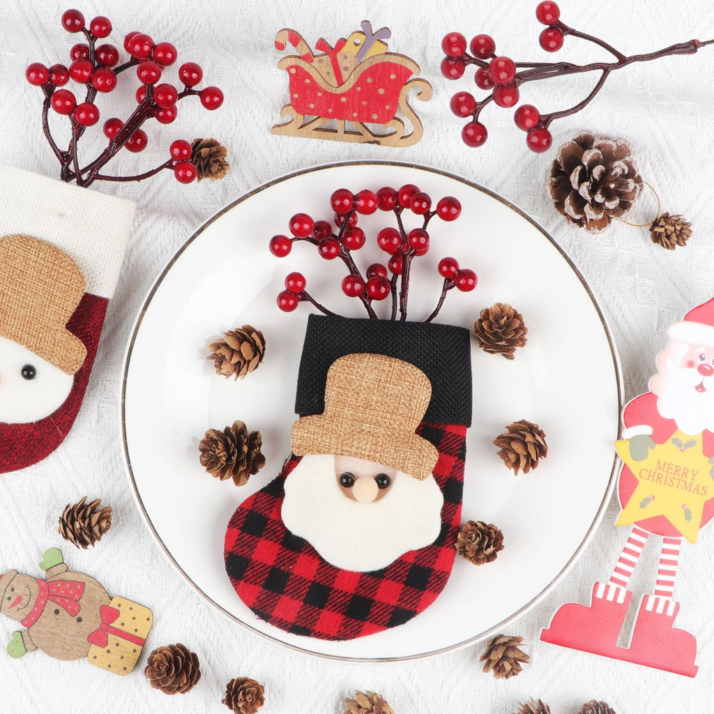 Christmas stocking with Santa face and red berries on a plate, surrounded by pinecones and holiday decorations.