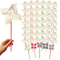 Hand holding a white pinwheel on an orange stick, with a large group of white pinwheels behind it.