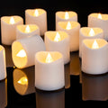Group of flameless LED votive candles with warm white flickering lights on a reflective black surface.