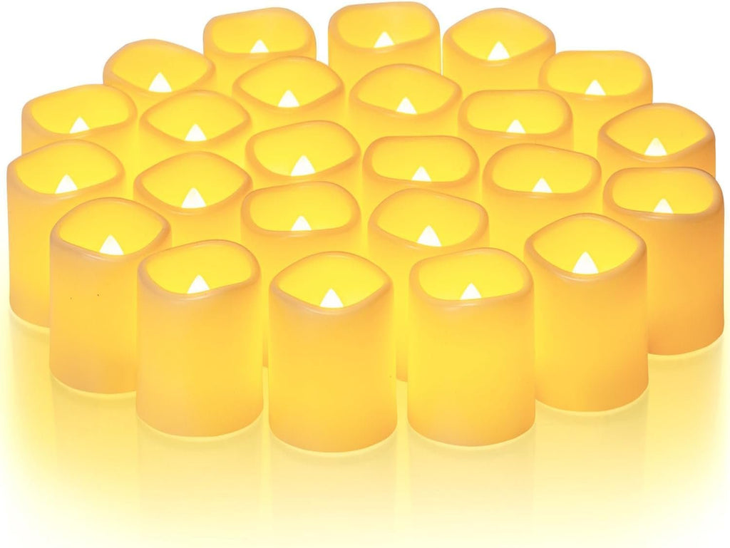 A group of 24 flickering flameless LED votive candles with warm white light, arranged closely together on a white surface.