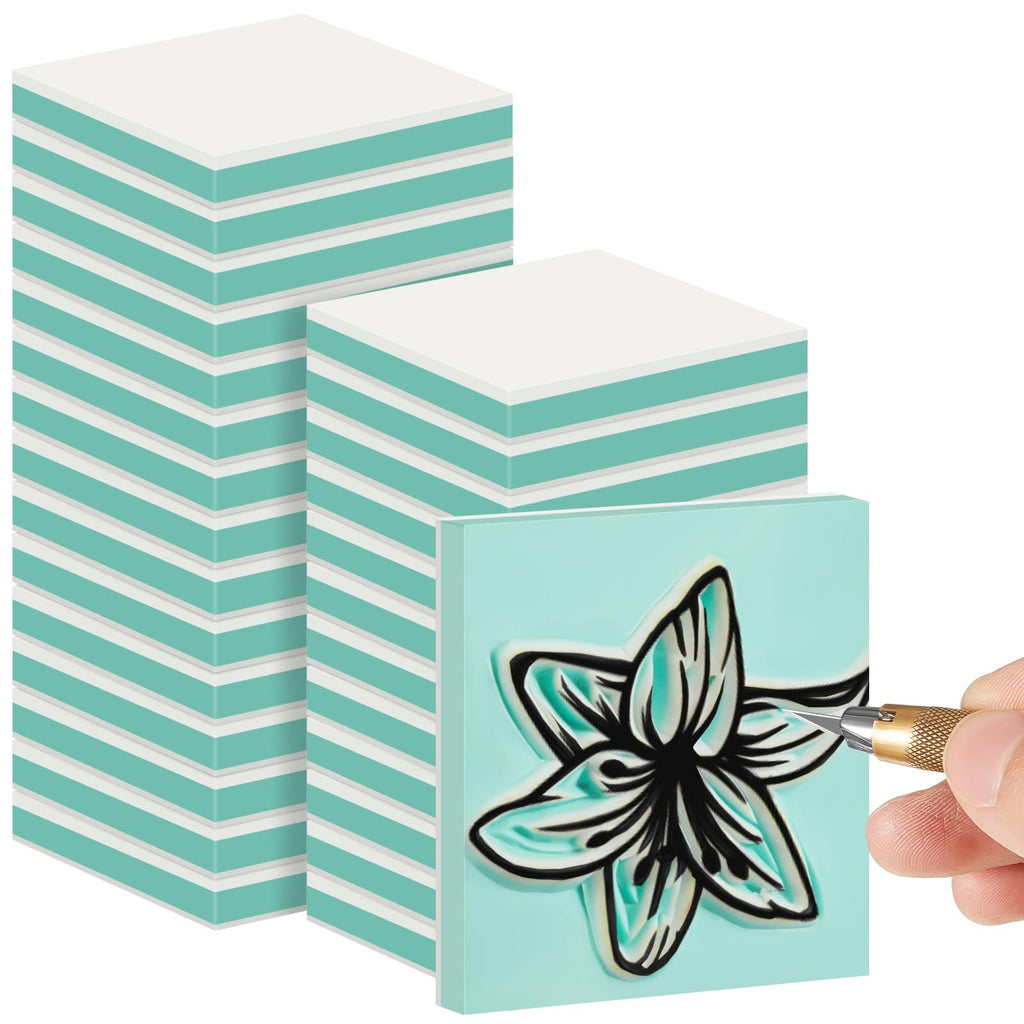 Stack of white and teal carving blocks with one block being carved with a flower design by a hand holding a craft knife.