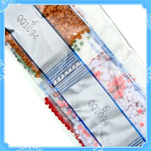 Diamond painting keychain kit with small colored rhinestones in sealed plastic bags, labeled QQ1094.