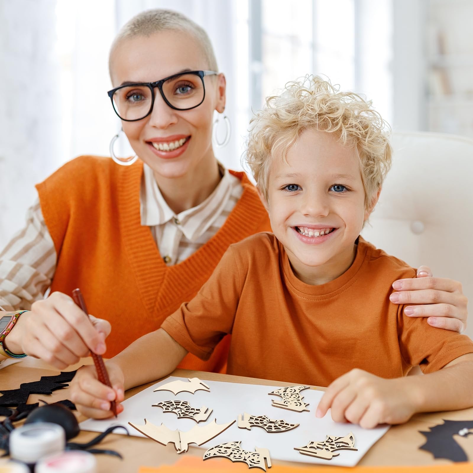 Woman and child crafting Halloween bat wooden cutouts on a table
