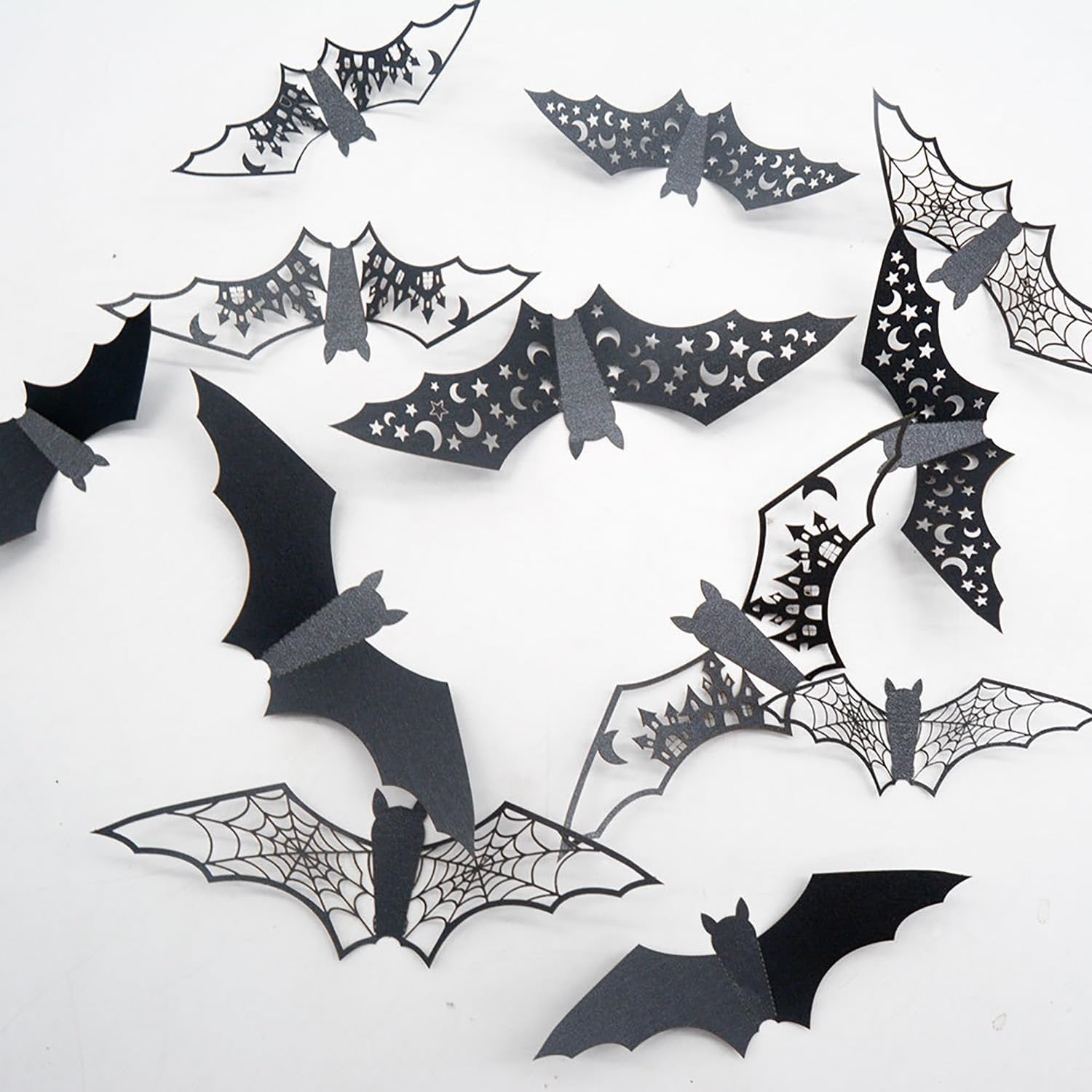 Assortment of black 3D vinyl Halloween bat wall stickers with various cut-out designs like spiderwebs and moons, arranged on a white background.