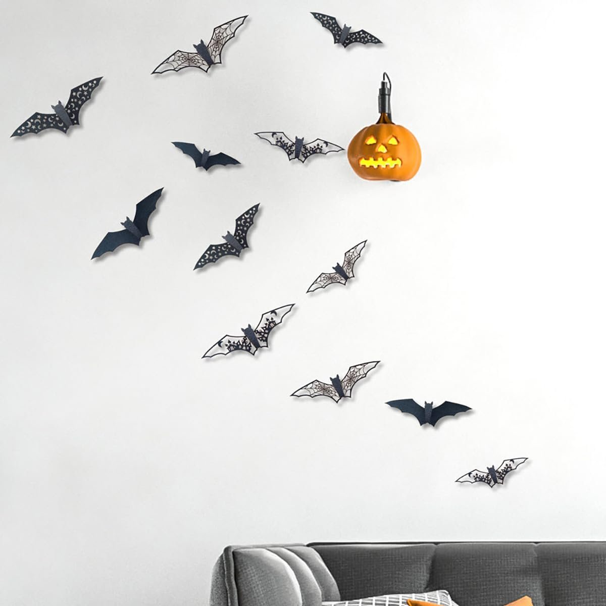 Halloween bat wall stickers arranged on a white wall with a carved pumpkin light