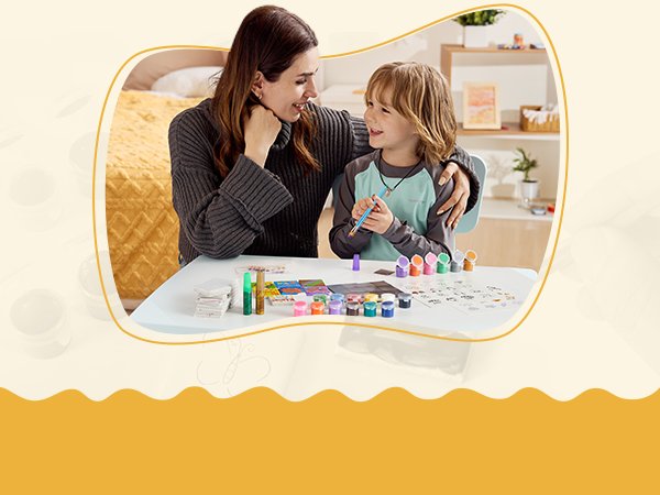 Mother and son painting magnetic tiles at a table, with art supplies spread out.