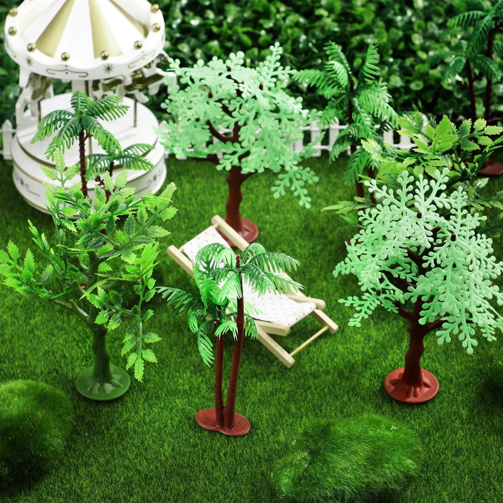 Miniature jungle trees and a carousel set on artificial grass with a tiny lounge chair.